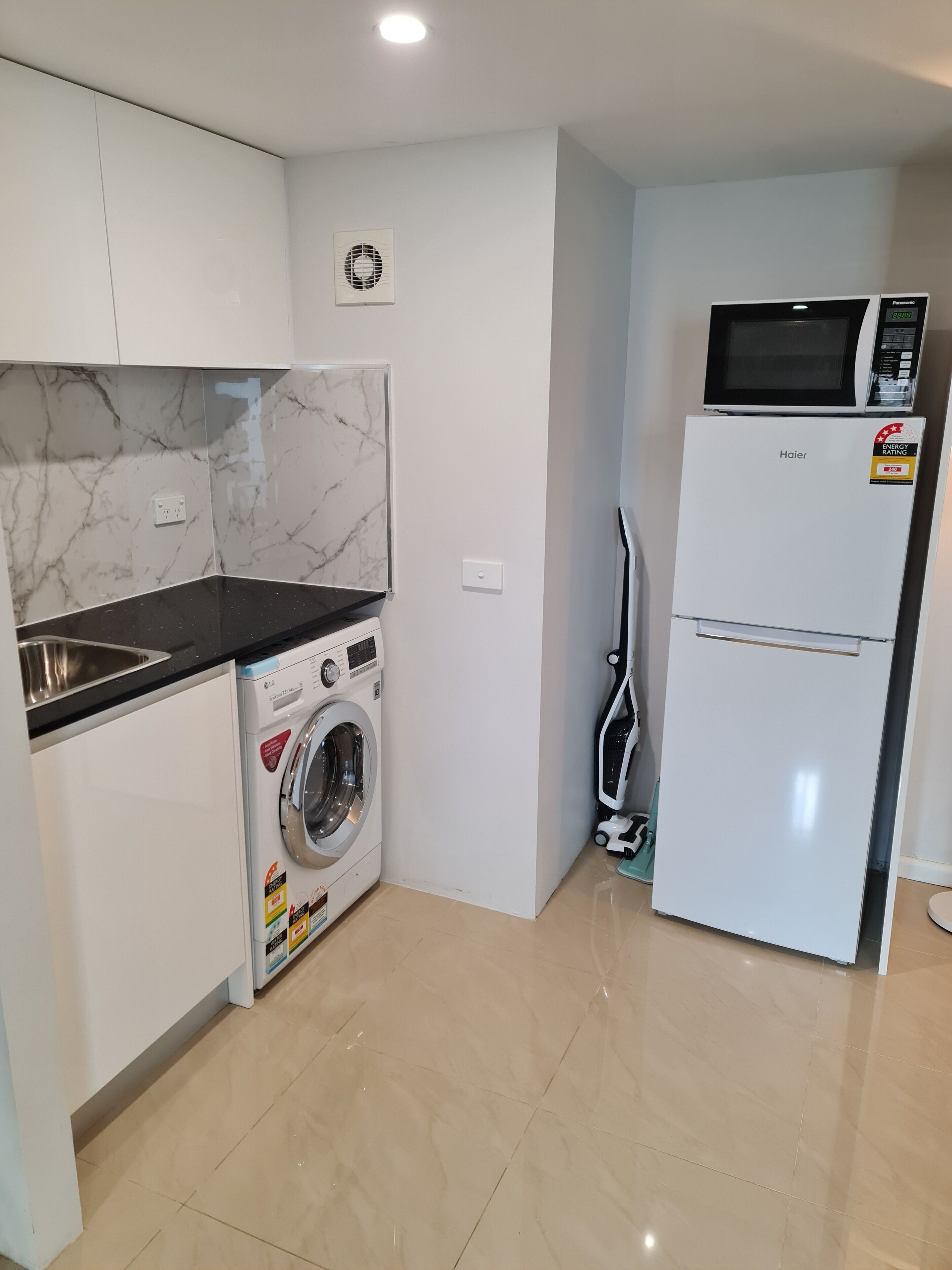 A compact kitchen with a washing machine, a microwave, and a refrigerator.