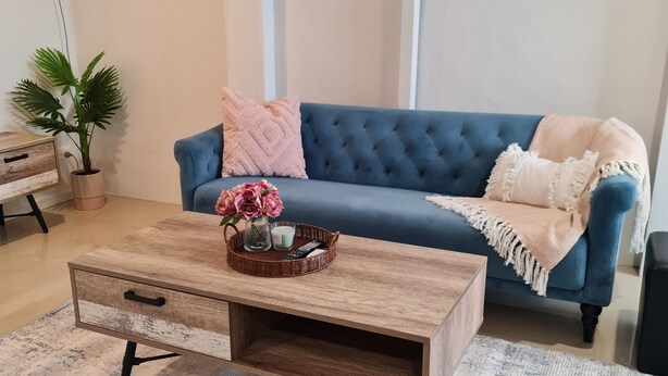 Un salon avec un canapé bleu, une table basse en bois et deux tableaux abstraits accrochés au mur.
