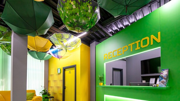 A reception area with a green wall, a reception desk, and a yellow door labeled "Dine Office". - Green cube hostel (Sofia)