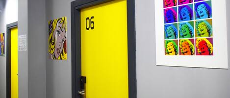 Un pasillo con puertas numeradas 06 y 07, cada una con una obra de arte distinta.