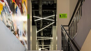 A staircase with a view of a colorful mural and a sign indicating rooms 13-18 and kitchen 2. - Green cube hostel (Sofia)