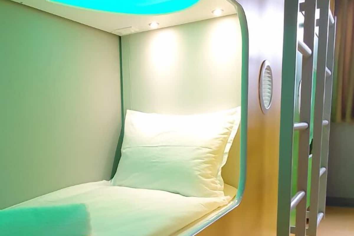 A bunk bed with a green and yellow color scheme, a pillow, and a light fixture above the bed.