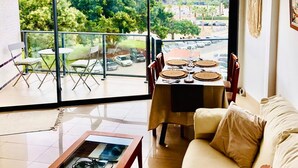 Un salon avec balcon, une table à manger dressée et un canapé.