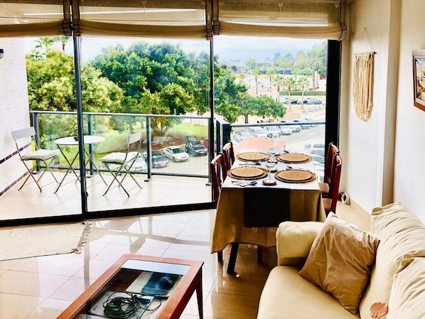 A living room with a balcony, a dining table set with plates, and a sofa.