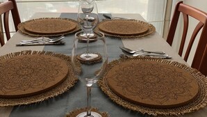 Une table à manger dressée avec des sets de table marron, un verre à vin et des couverts.