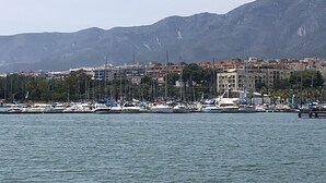 Un port de plaisance avec des bateaux amarrés, une vue sur la ville en arrière-plan et des montagnes.