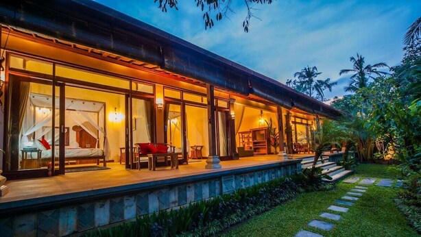 Ein modernes Haus mit Glasfassade, überdachter Veranda und gepflegtem Garten.