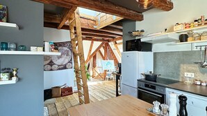 Eine rustikale Küche mit freiliegenden Holzbalken, einem Holztisch und einer hängenden Lampe.
