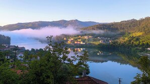 Ein friedliches Seeuferdorf mit Häusern und Windkraftanlagen im Hintergrund.