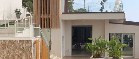 Un área de piscina moderna con vista despejada, sillas de descanso y una escalera que conduce a un edificio de diseño contemporáneo.