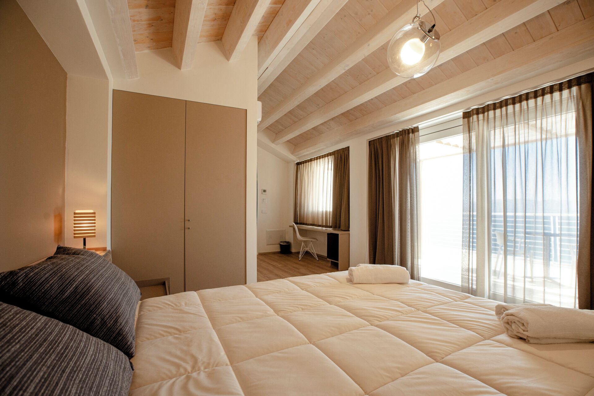 Un dormitorio con una cama grande, un escritorio y una ventana con cortinas.
