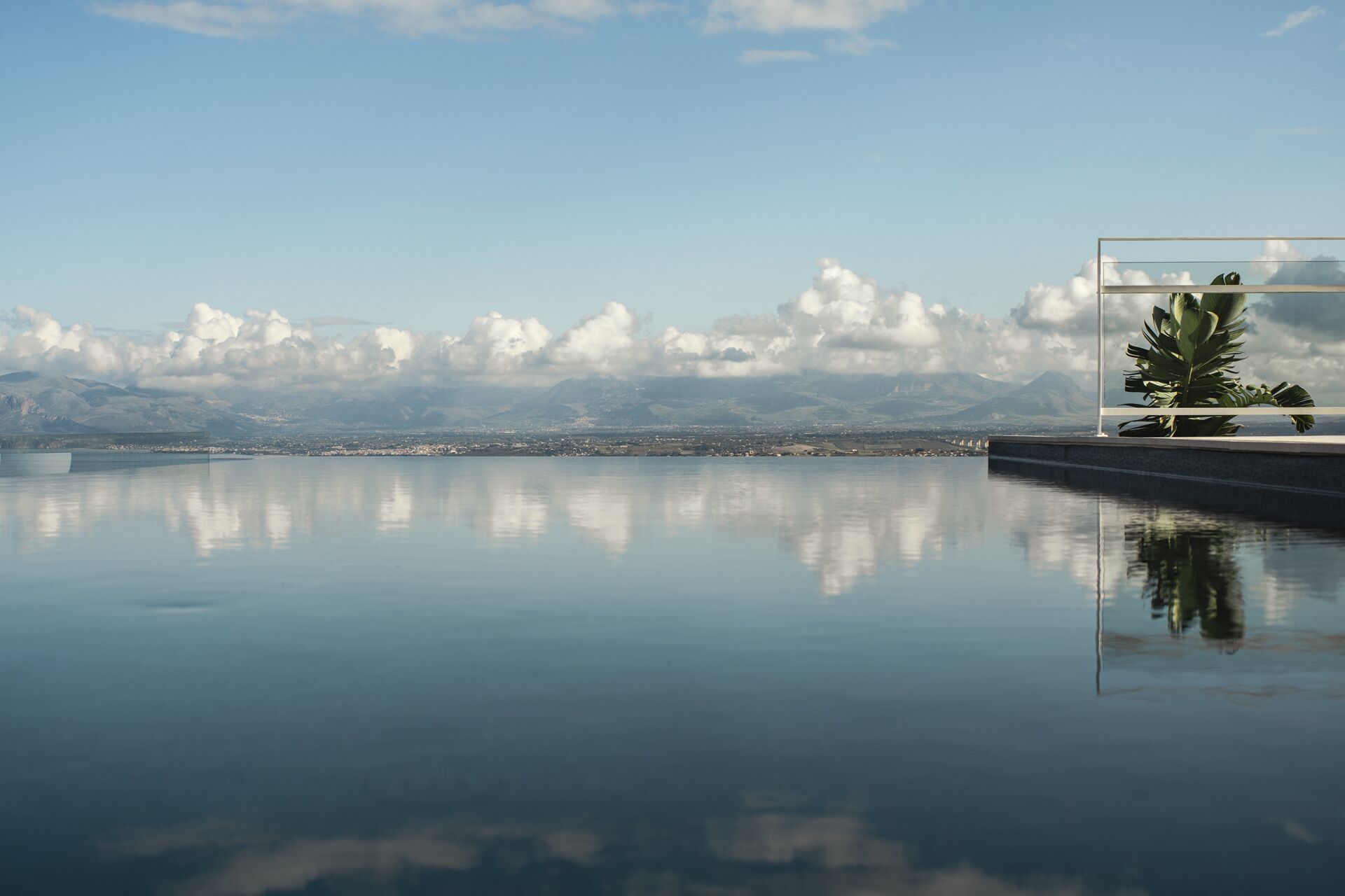 Een rustig overloopzwembad met een helder uitzicht op verre bergen en een stadsbeeld.
