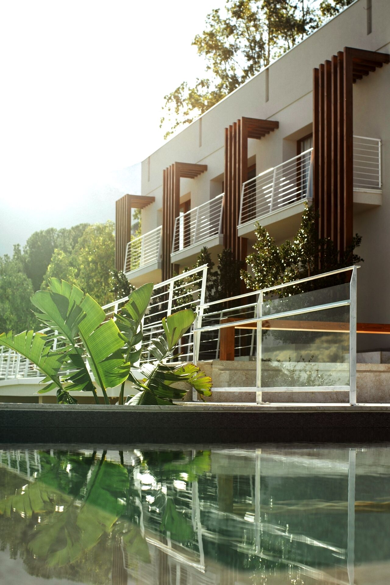 A modern building with balconies and a reflective pool.