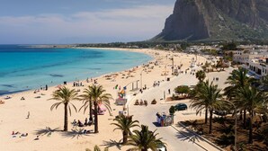 A beach with palm trees, a road, and buildings in the background. - Hotel Belvedere Resort 4 stelle (Castellammare del Golfo)