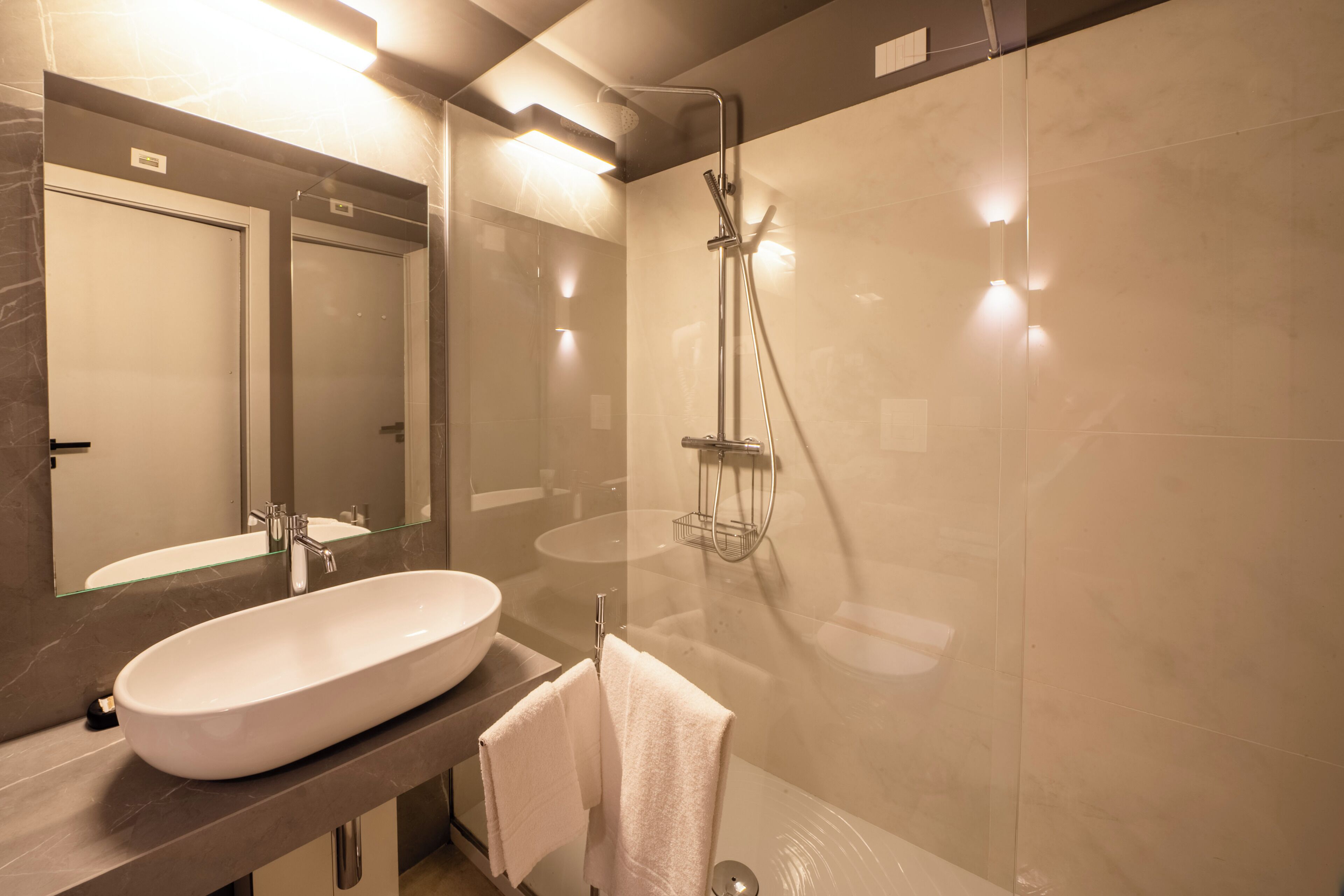 A modern bathroom with a large oval sink, a glass-enclosed shower, and a mirror above the sink.