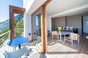 Varanda com mesa e cadeiras, porta de correr de vidro e vista para uma paisagem montanhosa.