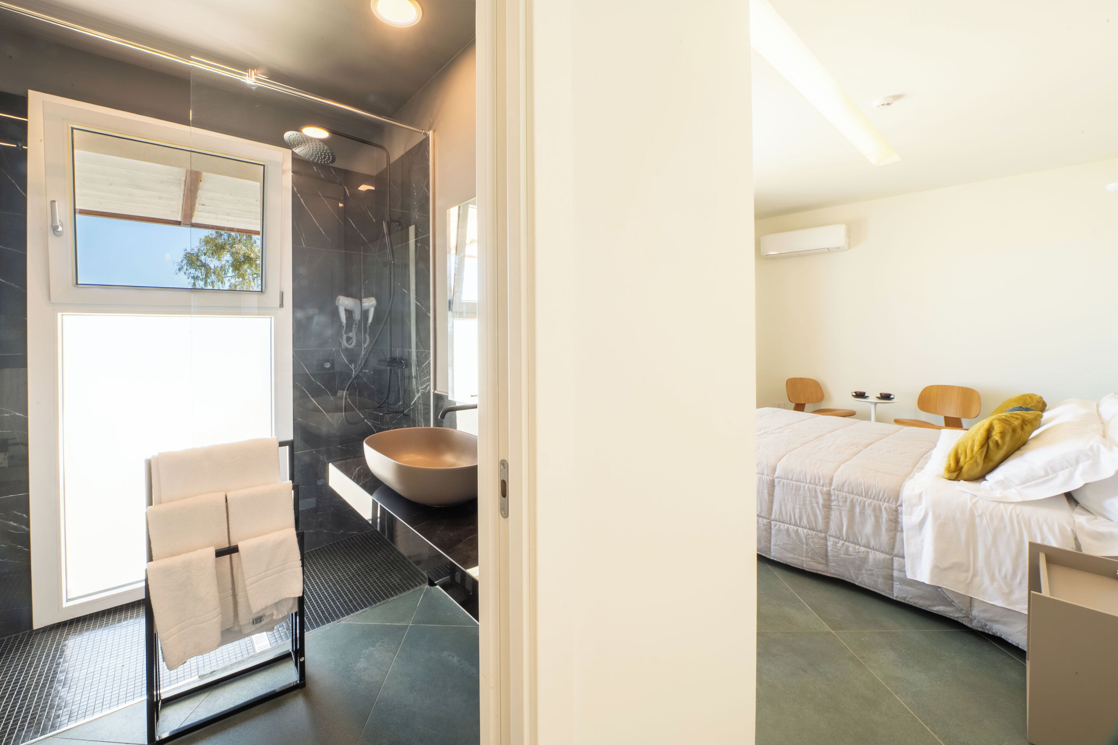 A modern bathroom with a glass shower enclosure, a large sink, and a towel rack.