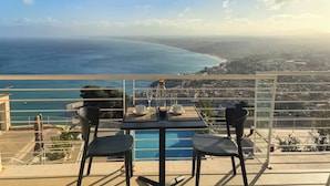 A terrace with a table and chairs overlooking a coastal city and ocean. - Hotel Belvedere Resort 4 stelle (Castellammare del Golfo)