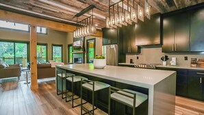 A modern kitchen with a large island, bar stools, and dark cabinetry. - MMMajesty: Pool, View, Secluded, Theater, Games, Hot Tub, WiFi, Yard, Fire Pit (Sevierville)