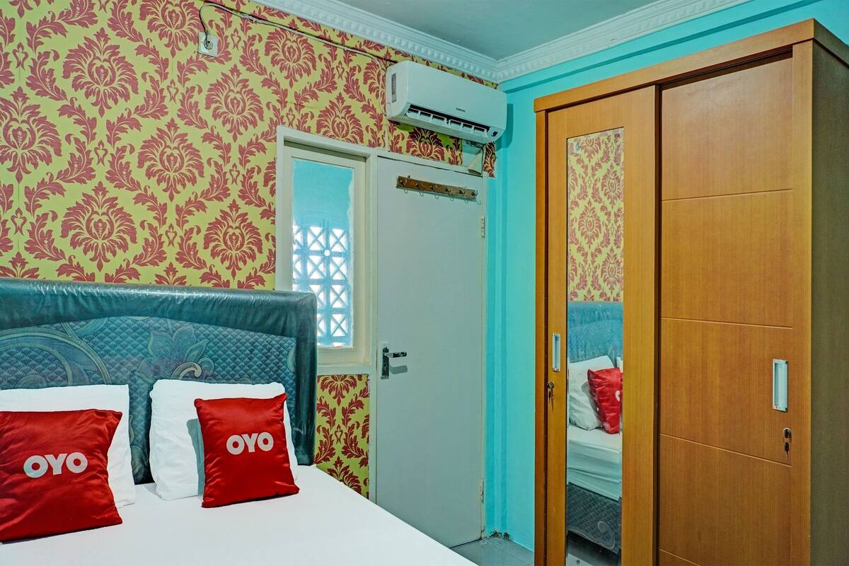 Un dormitorio con cama, dos almohadas con la marca 'OYO', un armario y un equipo de aire acondicionado.