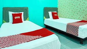 Two single beds with red and white bedding, a green headboard, and a floral-patterned wall. - Hotel O Home Stay Elis Cateliya Syariah (Karawang)