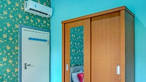 A room with a wooden wardrobe, a door with a lock, and a wall-mounted air conditioner. - Hotel O Home Stay Elis Cateliya Syariah (Karawang)