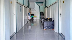 A hotel corridor with doors numbered 2 and 6, a staircase, and a seating area with a suitcase. - Hotel O Home Stay Elis Cateliya Syariah (Karawang)