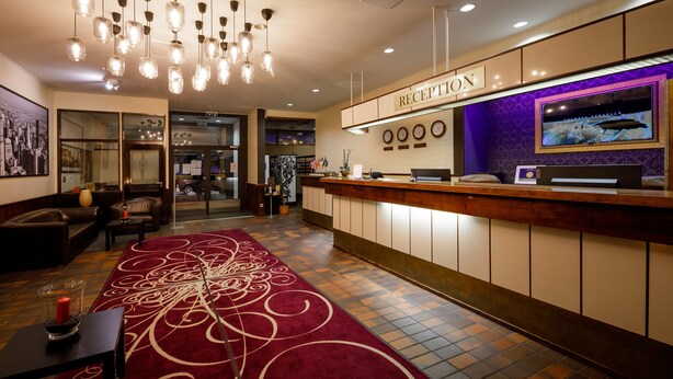 A hotel reception area with a reception desk, a large screen, and a red carpet. - Leikari Bungalows (Kotka)