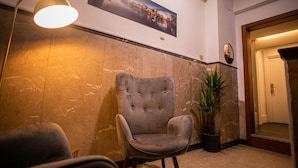A lobby with a marble wall, a tufted armchair, a floor lamp, a potted plant, and a framed picture. - 262 Boutique Aliados (Porto)