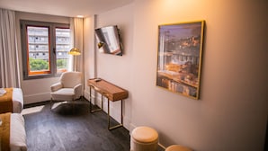 A hotel room with a bed, a chair, a desk, a window with curtains, a painting on the wall, and a view of buildings outside. - 262 Boutique Aliados (Porto)