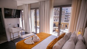 A hotel room with a large bed, a desk with a flat-screen TV, and a balcony with a city view. - 262 Boutique Aliados (Porto)