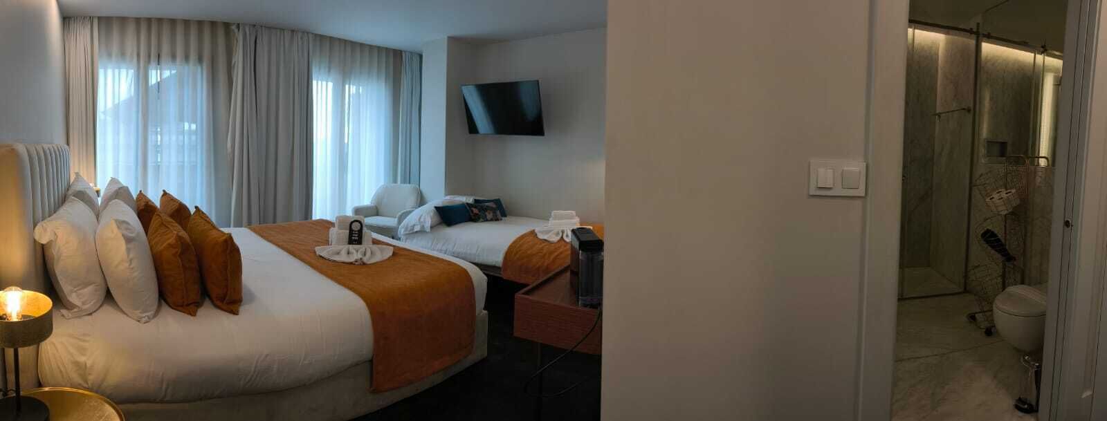 Ένα δωμάτιο ξενοδοχείου με δύο κρεβάτια, μια τηλεόραση, ένα γραφείο και μια περιοχή με ντους.