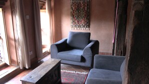Un salon avec un fauteuil gris, une table basse en bois et un tapis à motifs.