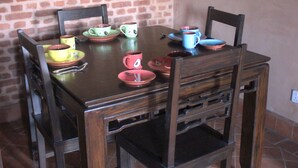 Une table à manger avec des chaises, entourée d’un mur en briques et posée sur un sol carrelé.