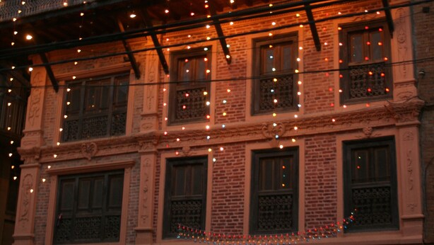 Un immeuble à plusieurs étages doté de balcons décorés de guirlandes lumineuses, de murs en briques et de poutres en bois traditionnelles.