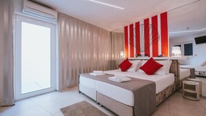 Habitación de hotel moderna con una cama grande, un televisor de pantalla plana y un ventanal corredizo al exterior.