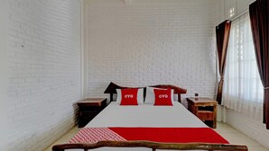 Una habitación con cama, paredes de ladrillo blanco y una ventana con cortinas.