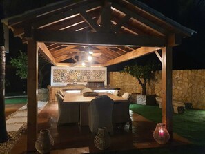 Une terrasse extérieure dotée d’une pergola en bois, d’un mur recouvert de carreaux et d’un mur en pierre.