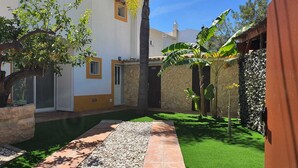 Un patio con piscina, césped artificial verde y un sendero de piedra.