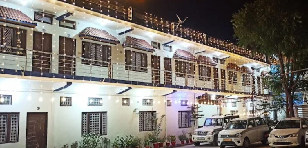 Un edificio de varios pisos con un estilo arquitectónico tradicional, que cuenta con varios balcones y una fila de coches estacionados al frente.