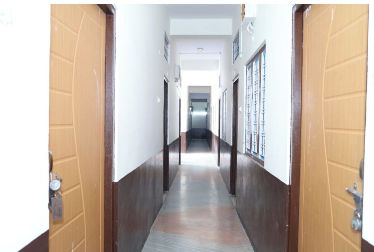 A narrow hallway with wooden doors on both sides, leading to a bright room at the end.