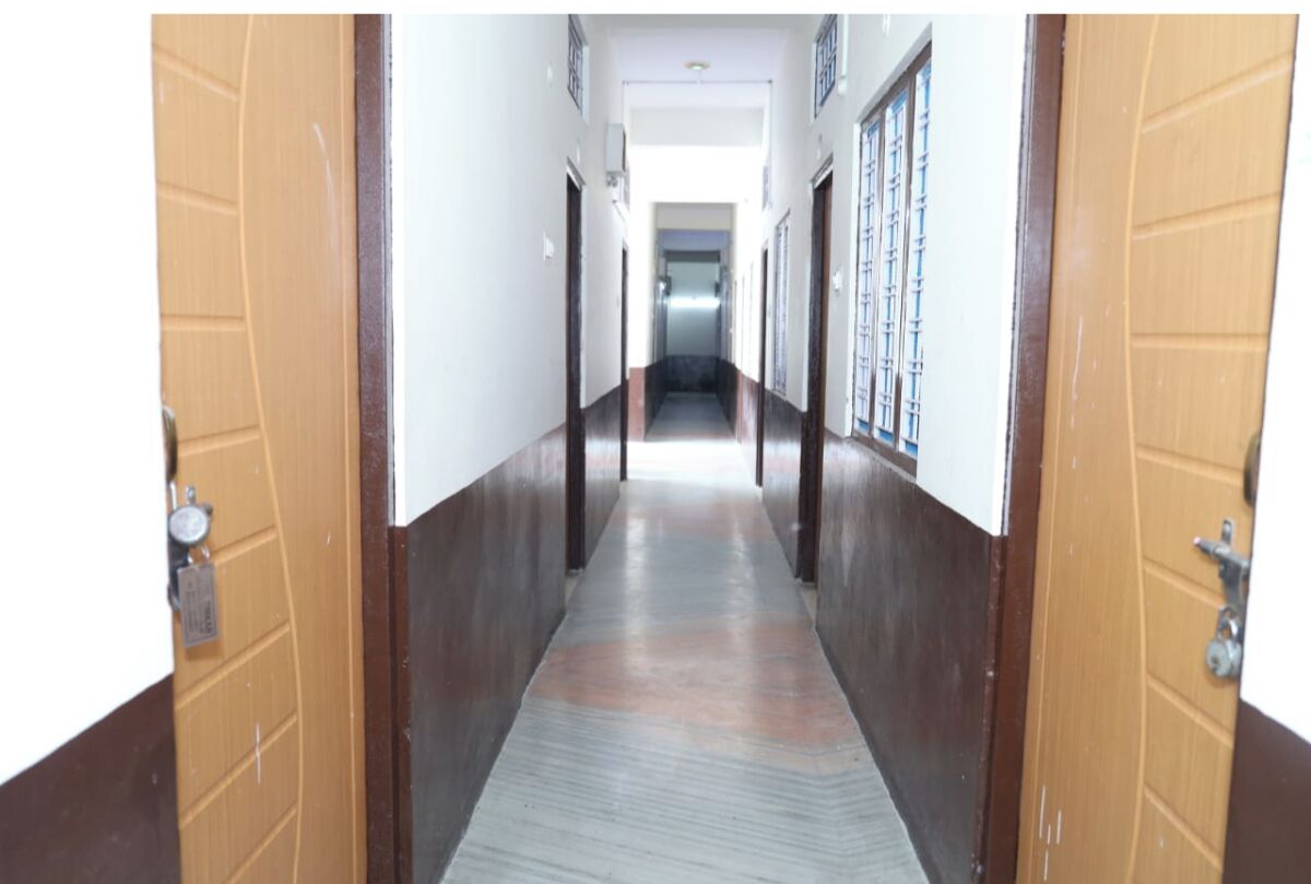 A hallway with wooden doors on either side, leading to a bright room at the end.