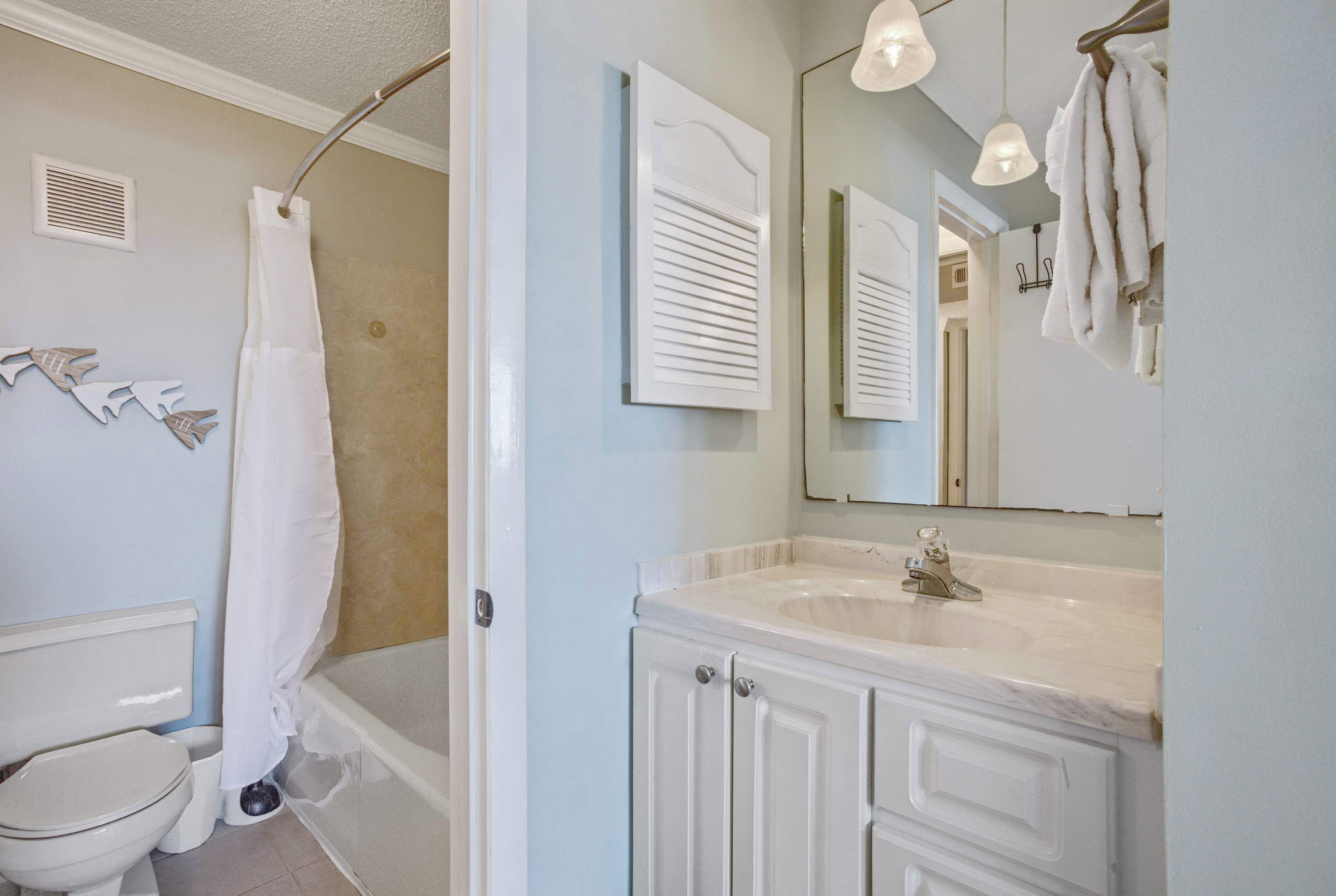 A bathroom with a toilet, bathtub, and a sink with a mirror above it.
