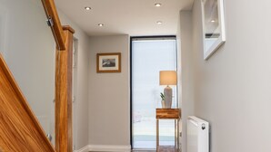 Ein Flur mit einer Holztreppe, einem gerahmten Bild an der Wand, einer Stehlampe und einer Heizung.
