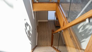 Eine moderne Treppe mit Holzwangen und Glasfeldern, die zu einer oberen Etage führt.