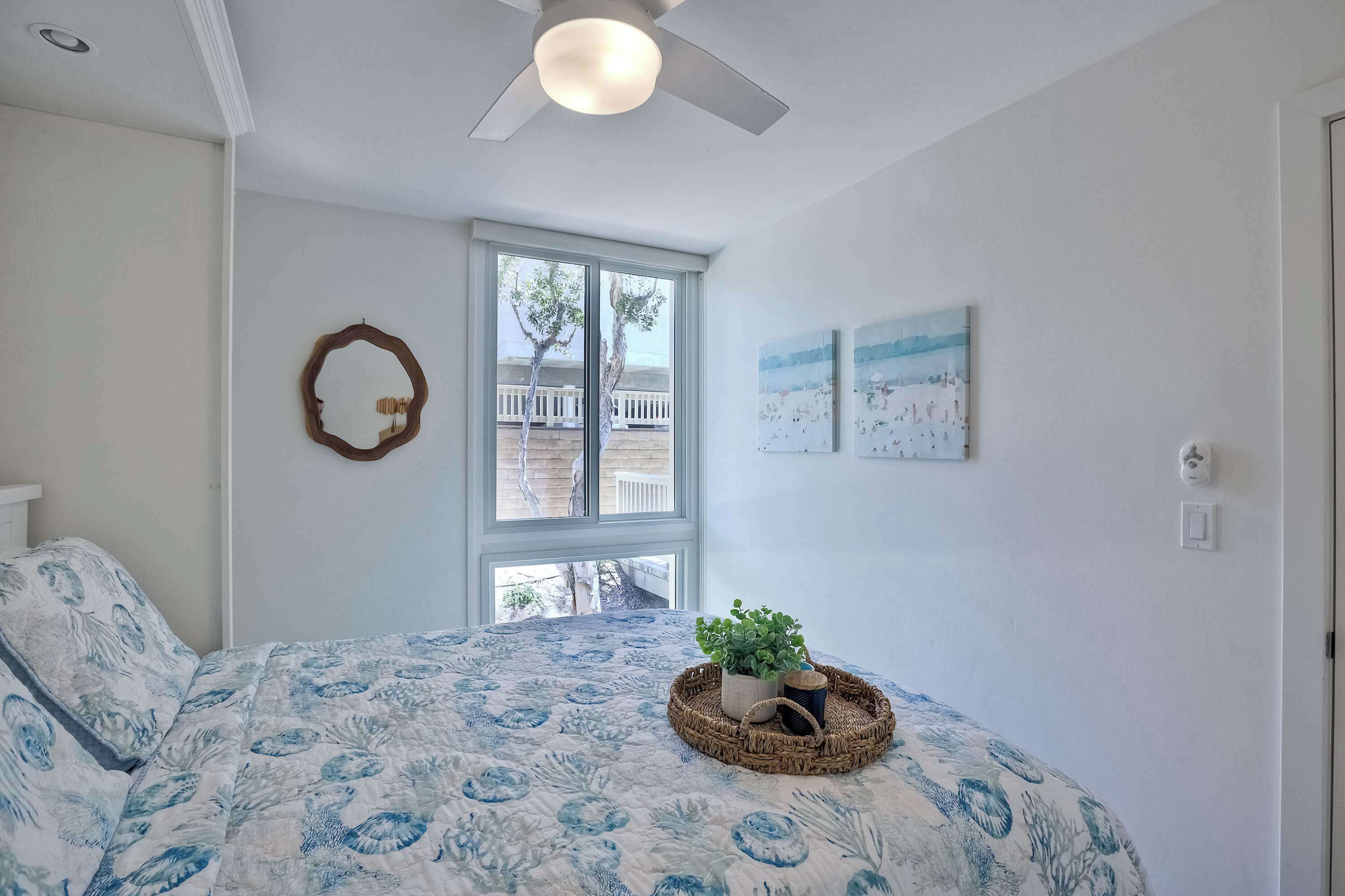 Una camera da letto con un letto, una ventola a soffitto, una finestra e decorazioni alle pareti.