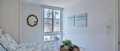 A bedroom with a bed, a ceiling fan, a window, and wall art.