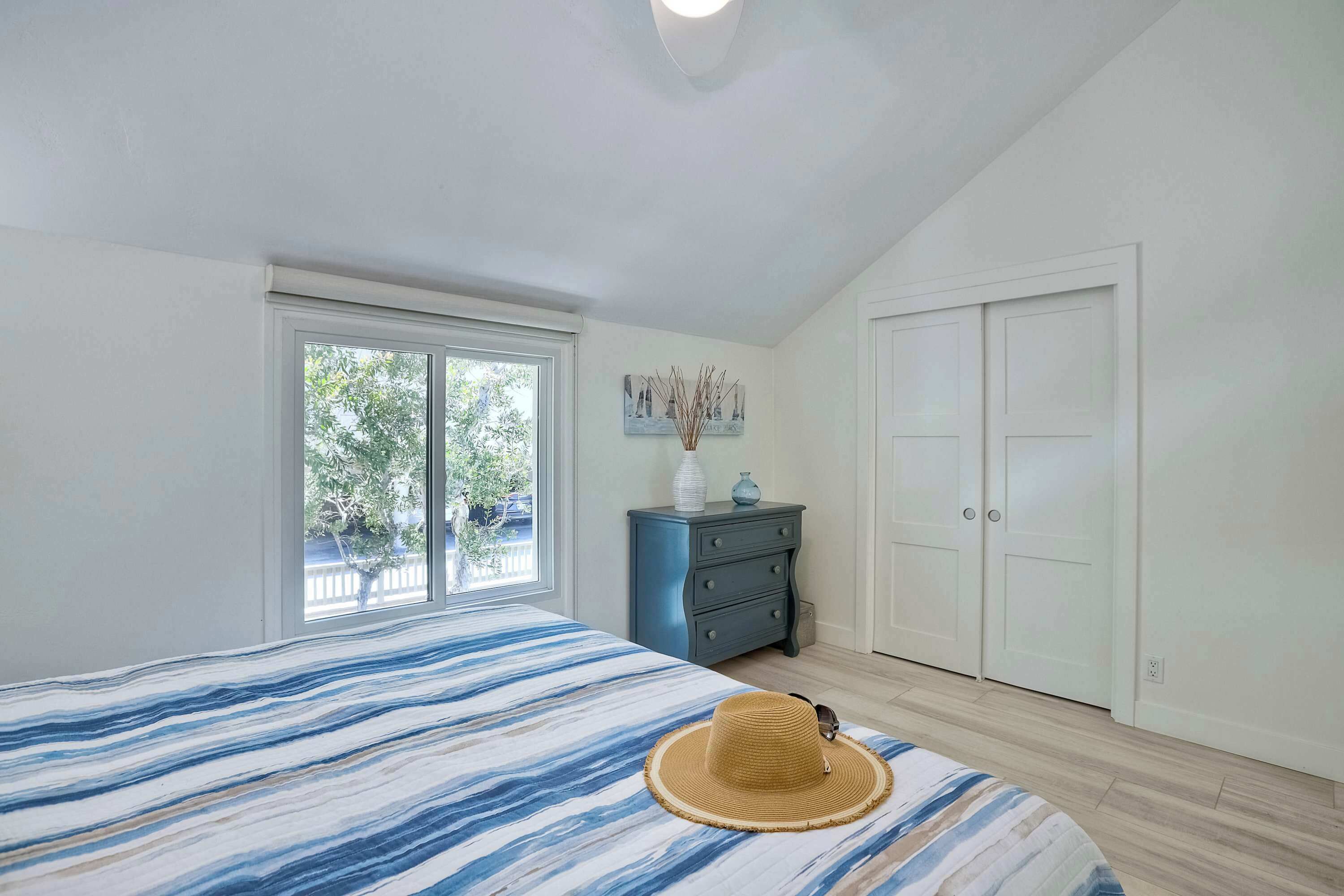 A bedroom with a bed, a window, a dresser, and a wardrobe.