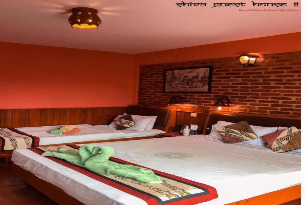 A hotel room with two beds, wooden headboards, a brick wall, and a ceiling light fixture.