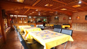 Un restaurante con mesas largas cubiertas con manteles amarillos, vigas de madera en el techo y paredes de ladrillo.